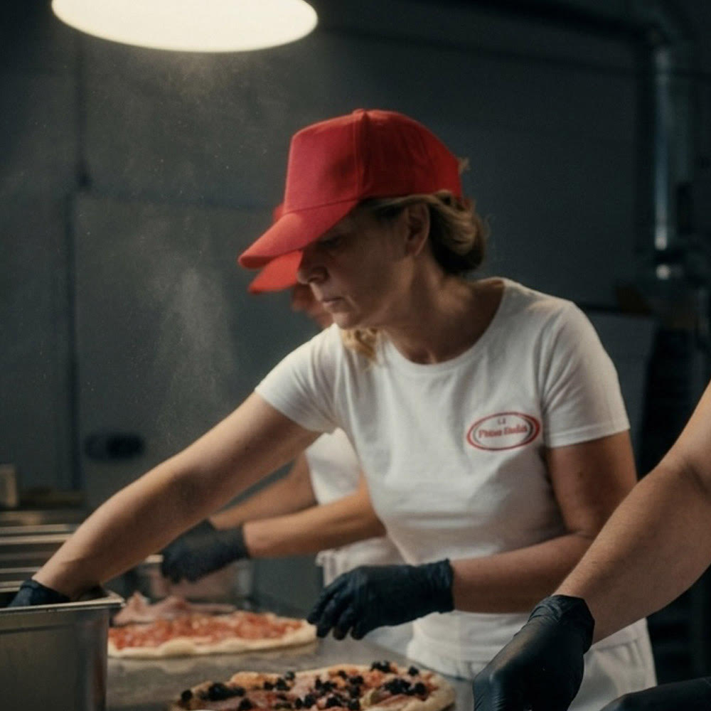 Een medewerkster van Pinsa Italia belegt pinsa’s in het Italiaanse atelier.